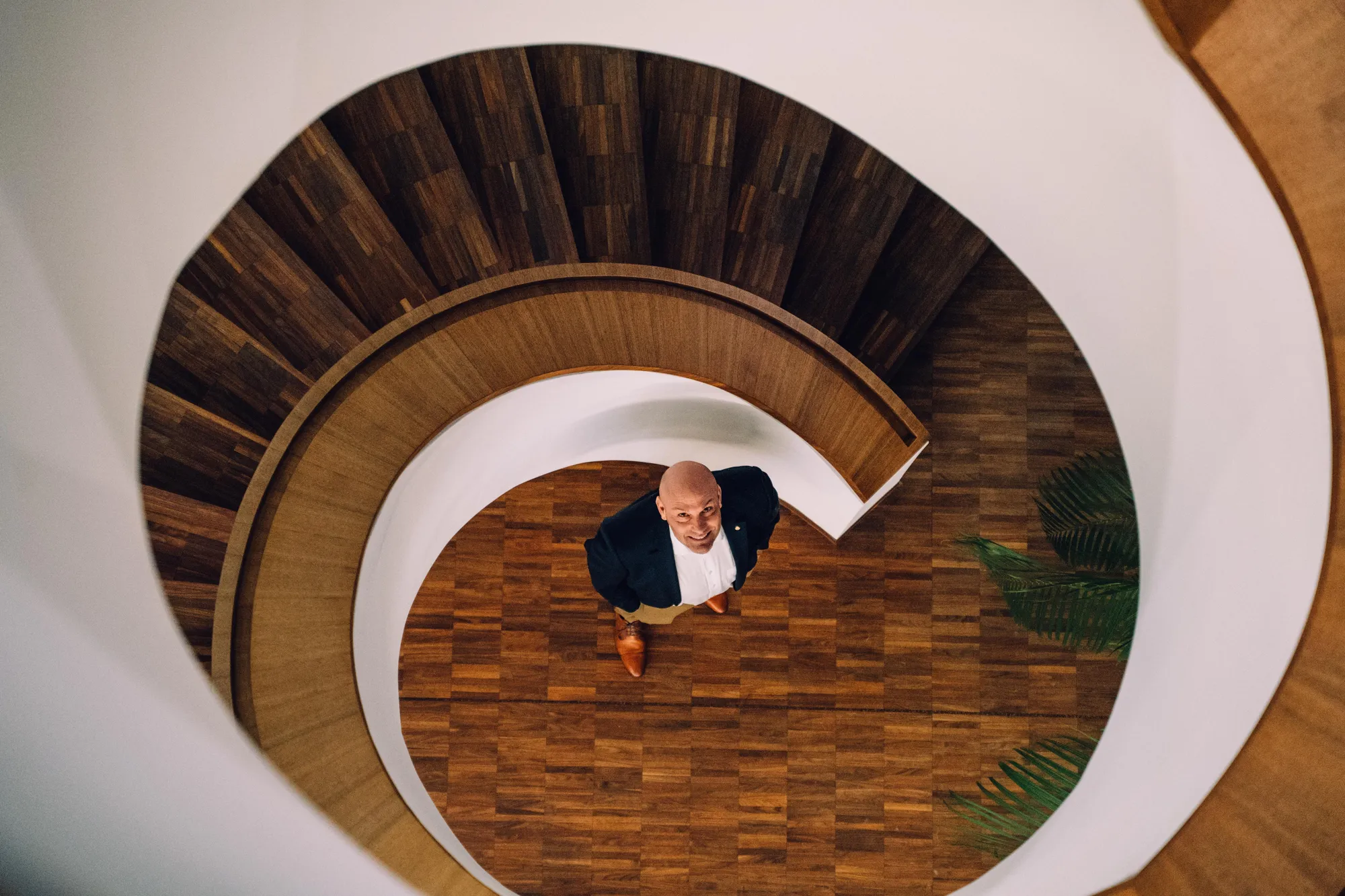 Blick von oben in eine Wendeltreppe aus Nussbaum. Unten steht André Feller und schaut hinauf.